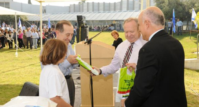 המלאך (במרכז) מעניק שי ליהושע מאור, פעם הספק של לאומי של המלאך והיום בחזקת בעלה של מאור, ולצידו אחד הנכדים. מימינו: אלון אלדר, מנהל אגף כוח אדם